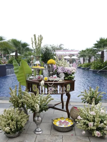 A traditional table setup for a Haldi ceremony by the pool, adorned with tuberoses and other auspicious items.