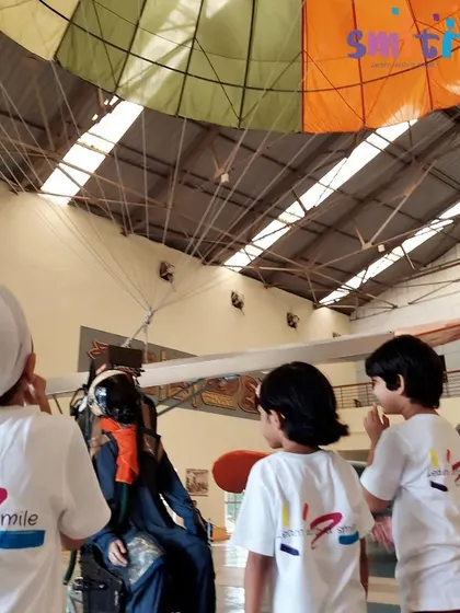Children look at a parachute and a pilot mannequin, learning about the equipment used in aviation.
