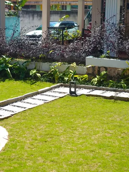 A different angle of the residential garden, showing the relationship between the raised plant beds, the lawn, and the stone well feature.