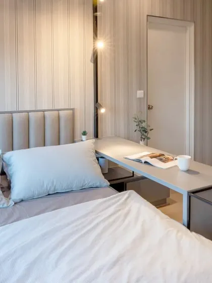 A close-up of the platform bed with its fabric cushioned headboard, set against a minimalistic wallpapered accent wall.