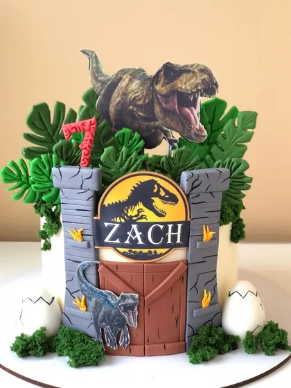 A thrilling Jurassic Park cake, with a T-Rex breaking through the park gates.