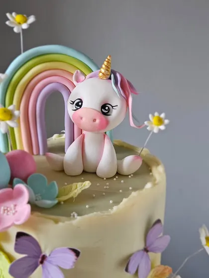 A close-up of the adorable, hand-sculpted unicorn topper. You can see the detail in her sweet expression and the pastel colors of her mane, all made from edible sugarpaste.