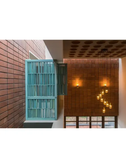 A view from the upper level of 'An Earthy Affair', showing the interplay of textures and light. The warmth of the brick walls and terracotta ceiling is balanced by a pop of color from the turquoise-painted library nook, creating a space that is both rustic and playful.