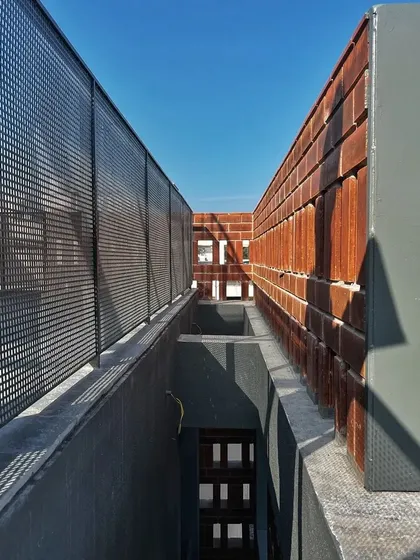 A work-in-progress shot showing the interaction of different materials. Here, you can see the contrast between the perforated metal screen, the warm brick, and the cool concrete structure.