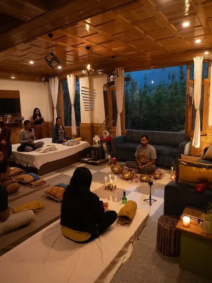 An intimate Full Moon meditation session held in a cozy, wood-paneled room. The candlelight and focused group energy create a truly special and uplifting atmosphere for healing and connection.