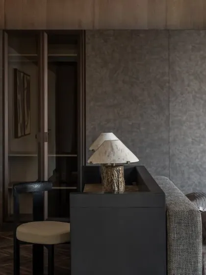 A detail of the master suite, showing the textured wall panels and the glass-fronted wardrobe. The abstract art adds a touch of personality to the otherwise calm and neutral space.