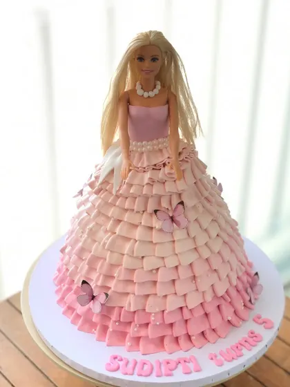 A side view of the Barbie doll cake, highlighting the detailed, hand-piped ruffles of her edible dress.
