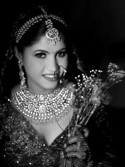 A beautiful black and white portrait of a bride holding a small bouquet, her smile lighting up the frame.