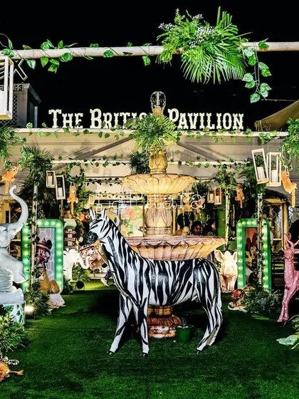 Another shot of the enchanting outdoor jungle setup at night, centered around a fountain and featuring a zebra, tiger, and other animal props.