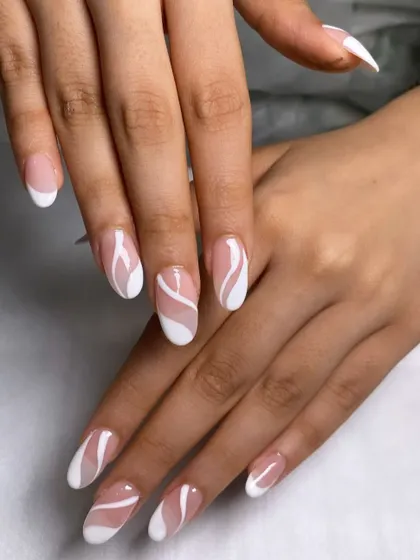 A modern take on a classic. This look features elegant almond-shaped nails with a creative, swirling twist on the traditional French manicure.