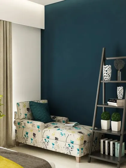 A comfortable chaise lounge placed against a deep blue accent wall creates a simple yet elegant reading corner in this bedroom.