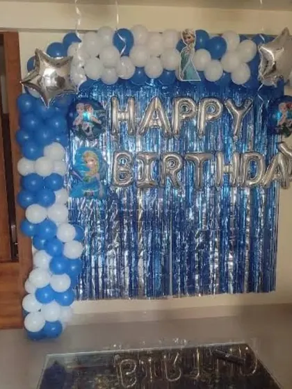 A 'Frozen' themed birthday party at home with a blue shimmer curtain and balloon garland.