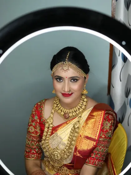 A bride looking stunning in a traditional red and gold saree, complemented by a full temple jewellery set.