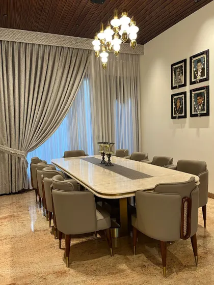 Another perspective of the grand dining room. The custom chairs feature a unique wooden detail on the back, adding a touch of bespoke craftsmanship to the elegant design.