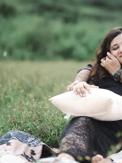 A tender moment from a pre-wedding picnic, where the bride-to-be rests peacefully in her partner's arms.