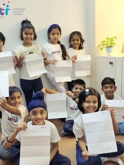 Our Montessori third-year students proudly hold up the letters they wrote to their parents. This activity combined writing skills with a real-world purpose.