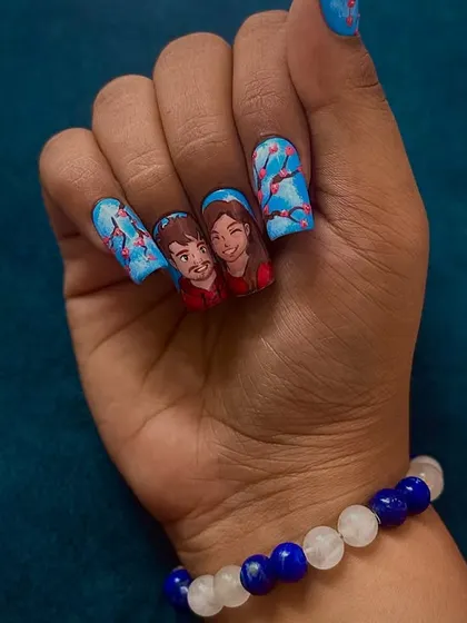 A close-up of the nails featuring the couple's portrait in the Ghibli style, with a background of cherry blossoms.