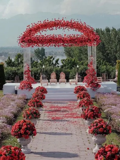 A wide-angle view of the stunning red floral mandap, showing the entire aisle lined with matching flower arrangements. This design creates a powerful visual impact for an outdoor wedding.