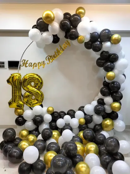 A classic black, white, and gold balloon ring for an 18th birthday, with large foil numbers and balloons filling the floor.