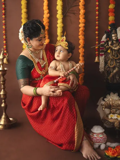 A mother looks lovingly at her baby Krishna, who is holding a small flute.