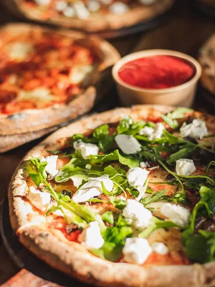 A spread of our pizzas ready for a wine pairing event. The variety, including a rocket and feta pizza, shows our ability to create custom menus for any occasion.