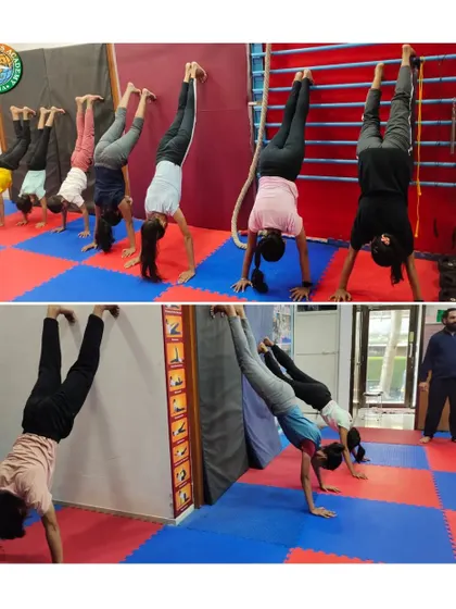 We focus on progressive strength building, as seen in this handstand practice session. Students use the wall for support to develop shoulder stability and balance, a foundational skill for more advanced yoga and gymnastic movements.