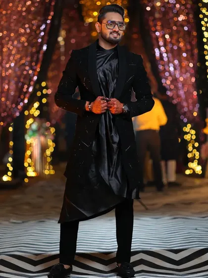 This black open Indo-Western jacket is detailed with pipe and katdana work. The draped koul kurta inside adds a touch of softness to the structured, modern look.