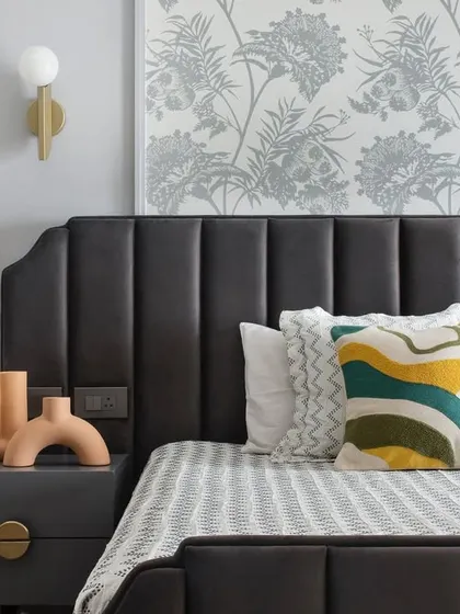 A close-up view of the bed, showing the interplay of textures and colors. The patterned wallpaper, geometric cushions, and warm terracotta vases create a visually interesting and cozy corner.