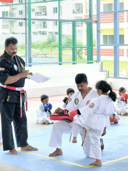 An examiner assesses a young student's kicking form during the karate grading event.
