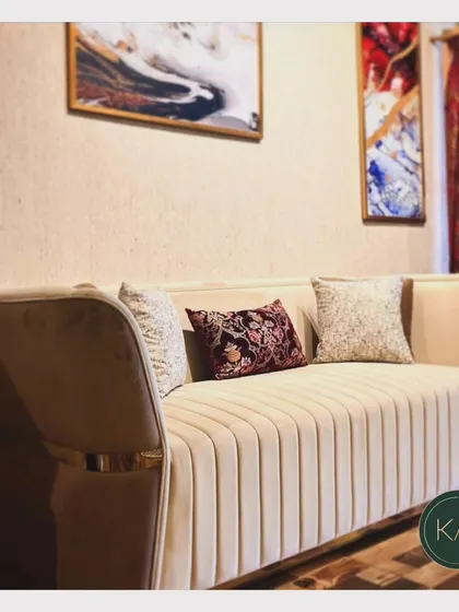 This sofa showcases vertical channel tufting in a soft beige fabric, accented with a metallic band at the base. It's a design that balances modern trends with timeless comfort.
