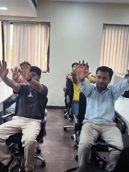 A close-up of employees practicing a seated spinal twist. This gentle movement helps to increase spinal mobility and relieve lower back tension, a common issue in corporate environments.