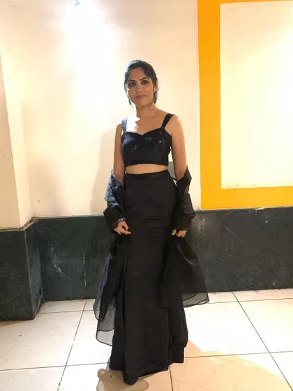 Perfect for a cocktail night, this all-black ensemble features a sequined crop top paired with a satin fish-cut skirt. The look is completed with a sheer organza jacket for a touch of drama.
