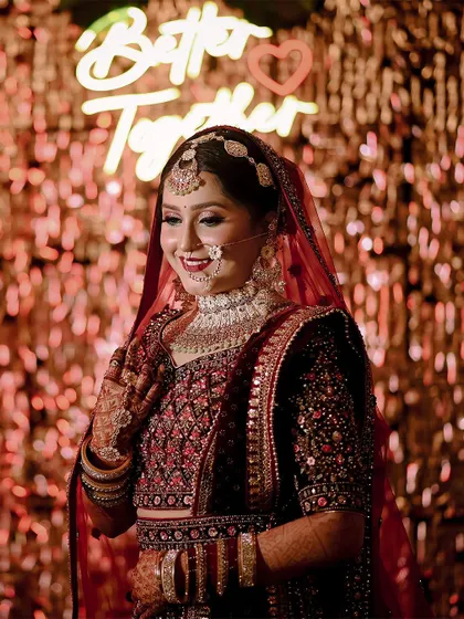 A smiling portrait of the bride in front of a "Better Together" neon sign.