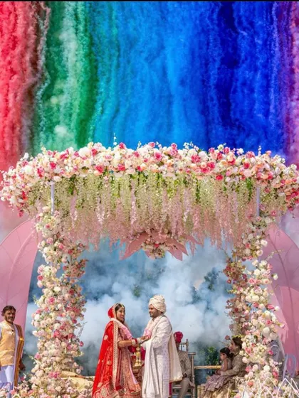 A close-up of the beautiful pink floral mandap with a rainbow of color smoke in the background. This is a perfect example of how I combine decor with special effects for a memorable varmala.