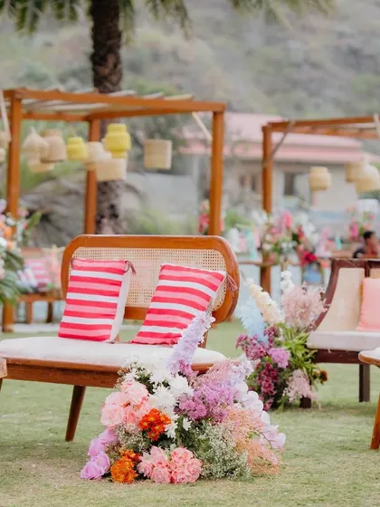 Grounded floral arrangements add lushness and color at every level. Here, a mix of pinks, oranges, and whites brings life to the lounge seating at this outdoor Mehendi.