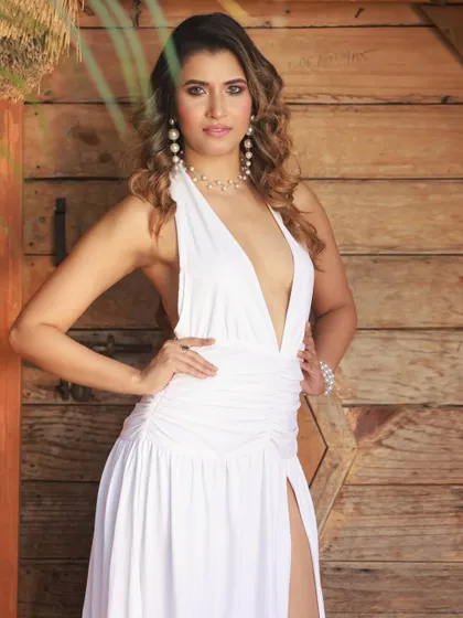 A confident, hands-on-hips pose against a wooden door, highlighting the dress's plunging neckline.