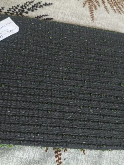 A clear view of a standard turf backing with drainage perforations. These holes are essential for outdoor installations to allow rainwater to drain through.