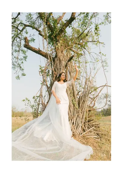 A stunning bridal portrait set against a dramatic natural backdrop. The long, flowing train of the gown and the bride's elegant pose create a truly breathtaking and artistic image.