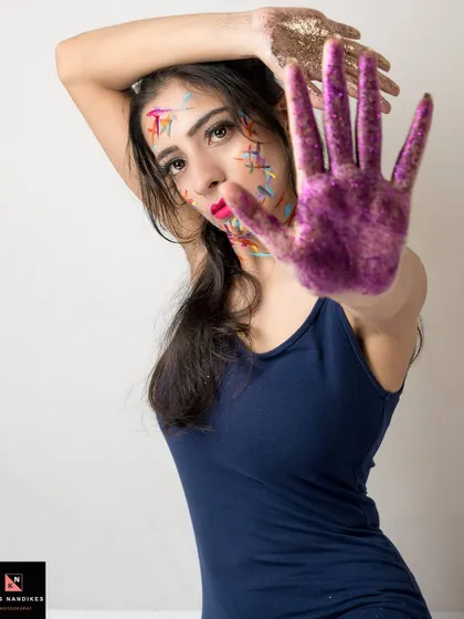 A powerful pose from the 'Glitter' series where the model holds up a glitter-covered hand as if to say stop. This shot combines creative makeup with a strong, expressive gesture.