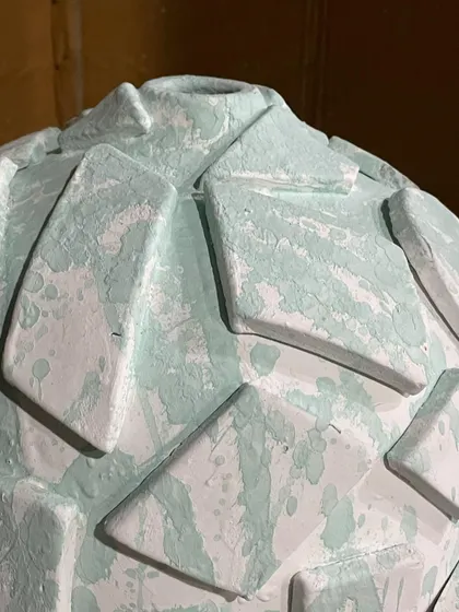 A close-up of the geometric patterns on the globe vase. You can see the texture of the applied glaze, which will melt and flow in the kiln to create a rich, varied surface.