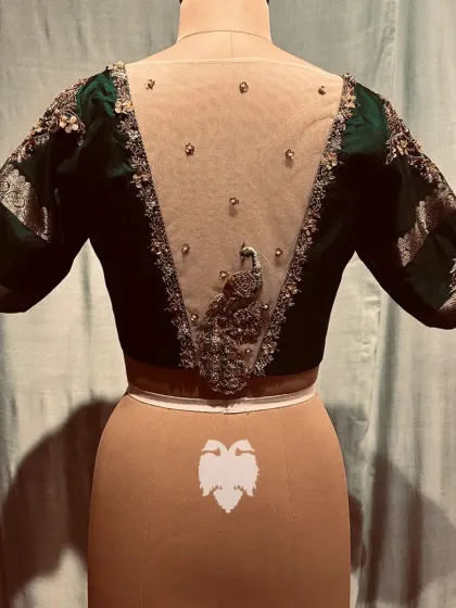 The sheer back of the bottle green blouse, with the peacock as the stunning centerpiece.