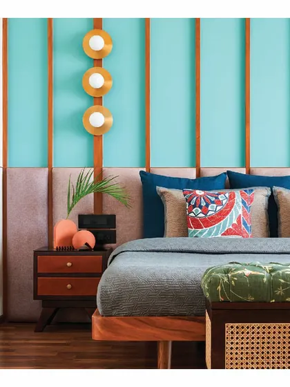 This vibrant bedroom features teal blue walls with wooden rafters. We designed a custom teak wood bed with a taupe fabric headboard to balance the bold wall color, creating a space that is colorful, modern, and warm.