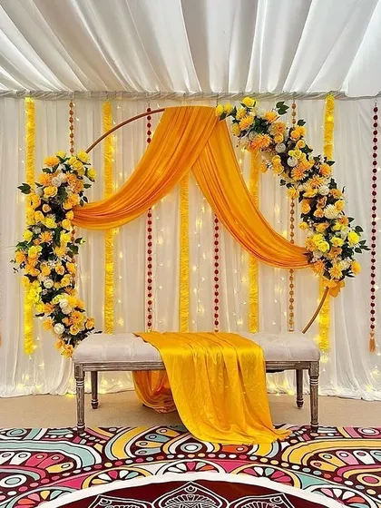 A beautiful Haldi ceremony setup with a floral ring draped in yellow fabric and decorated with yellow and white flowers.