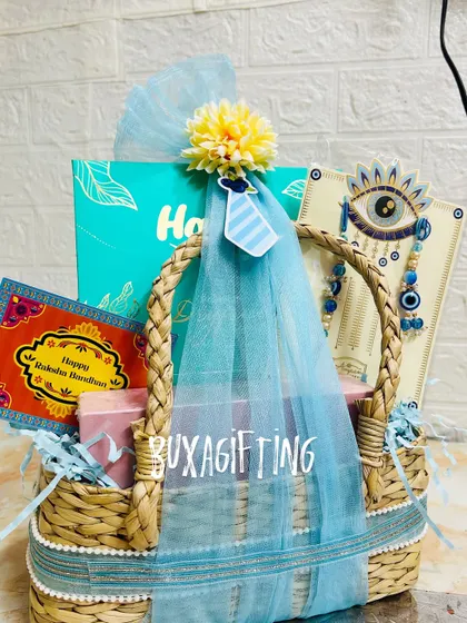 The full view of the blue-themed Rakhi hamper, showing the gift box, rakhi set, and greeting card inside the woven basket.