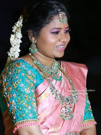 A side profile of the bride, showing the detail on her layered AD stone necklaces and matching jhumkas.