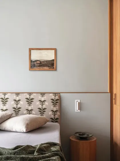 A detail of the bedroom in Apartment 3201, where a patterned headboard and a small piece of art add personality to the minimal space.