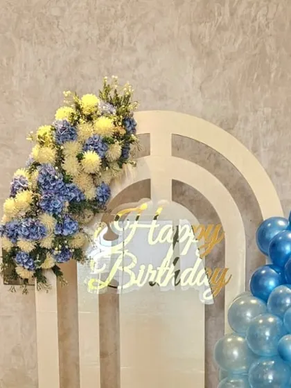 We love combining different textures. The softness of the flowers contrasts beautifully with the sleek, reflective surface of the birthday sign and the clean lines of the white arch panel.