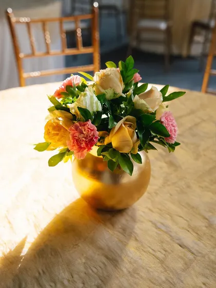 A simple floral centerpiece in a golden vase.
