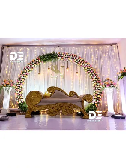 A classic ring ceremony stage with a full floral arch against a backdrop of fairy lights. The clean white stage and pillars elevate the look, making the floral colors pop.