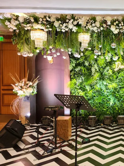 Another angle of the Sangeet stage, showing the musical equipment in place. The combination of the green wall, hanging chandeliers, and patterned floor creates a visually dynamic setting for performers.